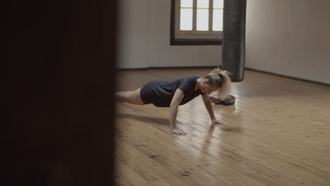 Long-shot-of-focused-woman-doing-push-ups-in-practice-room